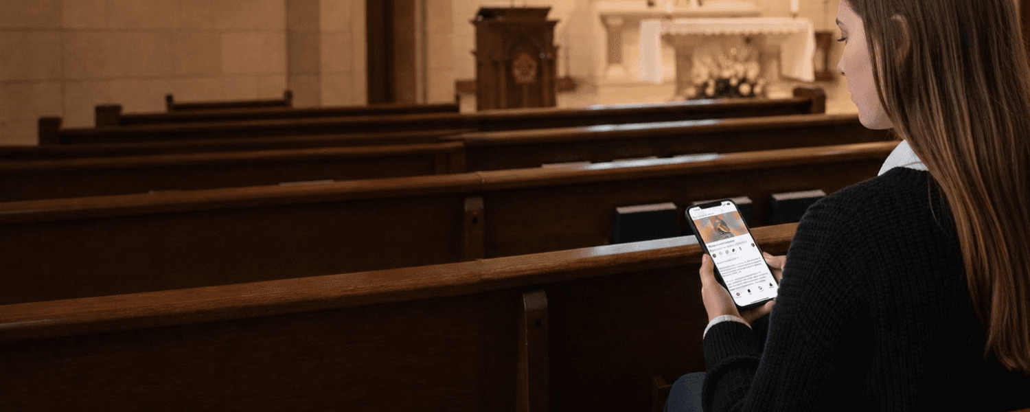 A young woman reading the TAN Digital app in a quiet church pew