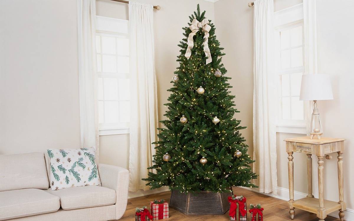 lightly decorated prelit Christmas tree in the corner of a neutrally decorated living room