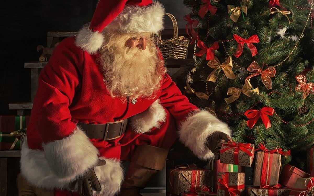 Santa Claus placing presents under Christmas tree