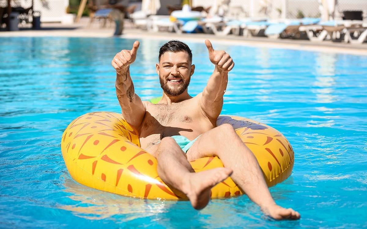 adult male smiling, giving thumbs up from pineapple print pool tube