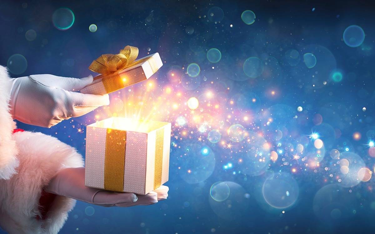 gloved santa hands opening a box with sparkles and glitters flowing out of it