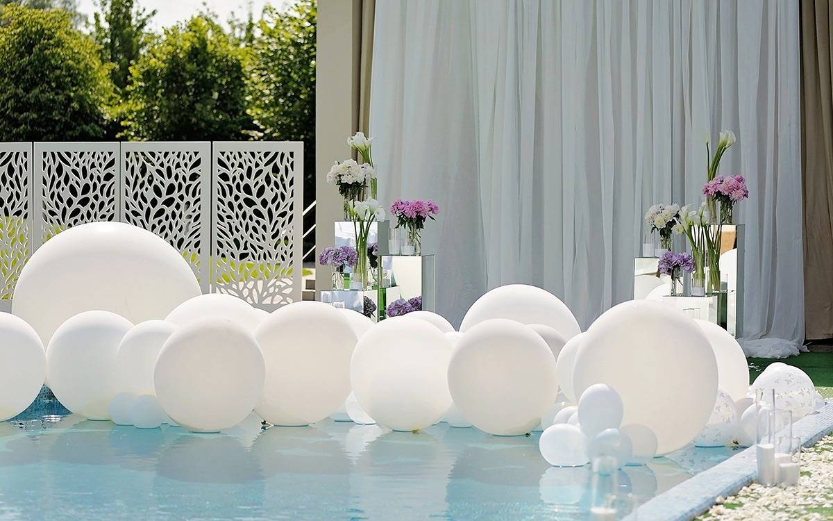 inground swimming pool decorated with flowers and white balloons in various sizes