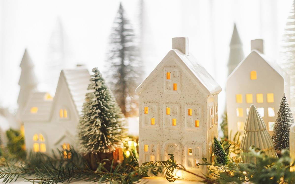 white ceramic Christmas village houses with lights, pine greenery and bottle brush trees
