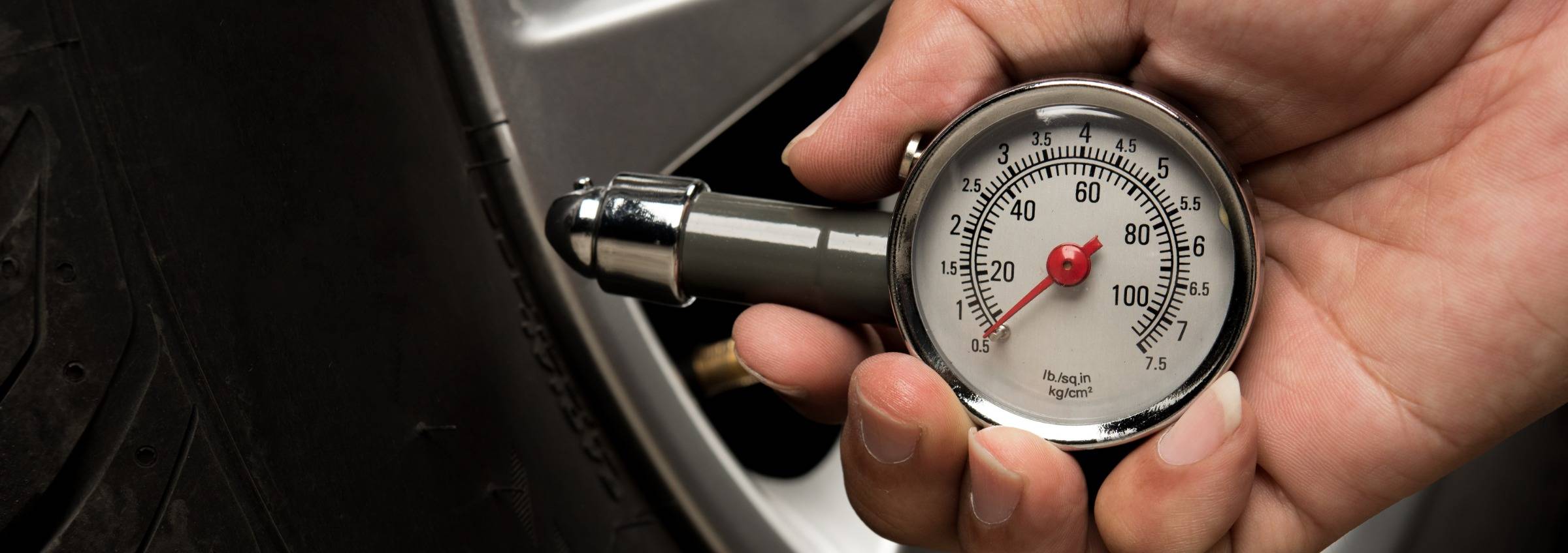 Persons hand holding PSI measuring tool (analog dial gauge)