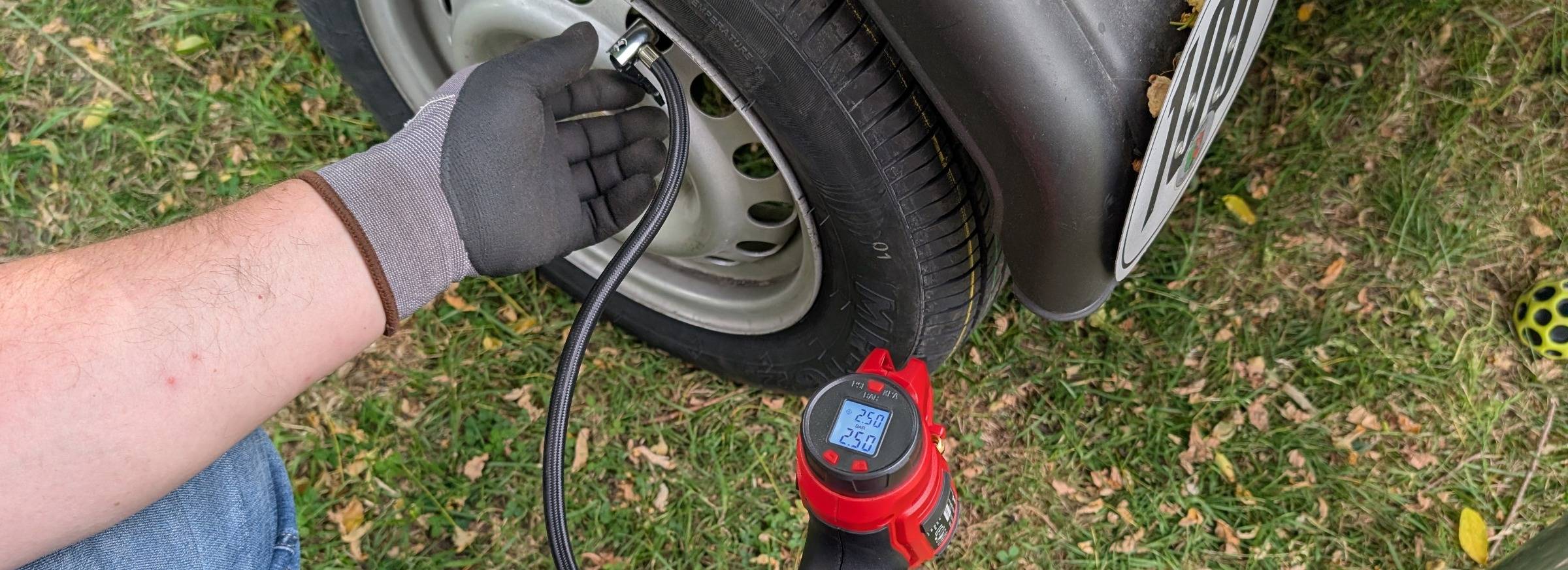 Tire on grass a person adding air from handheld machine to tire