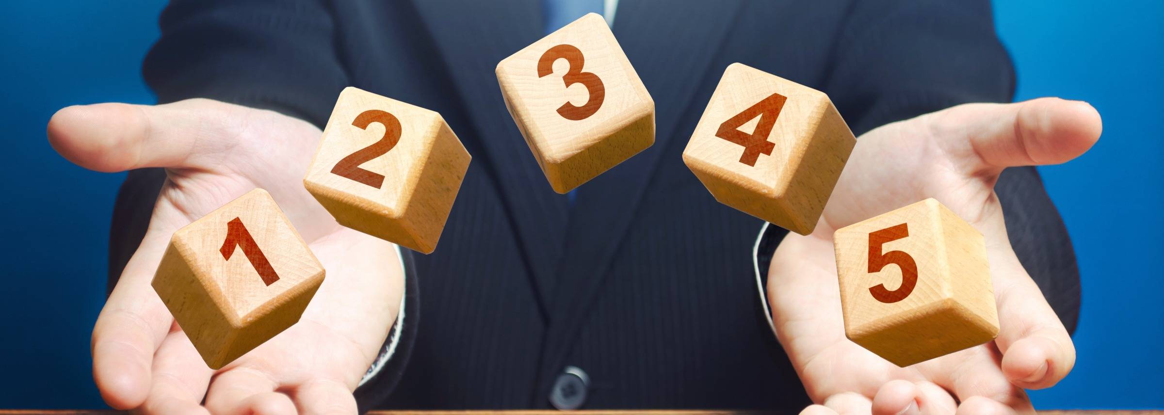 Wooden blocks floating in air with individual umbers on them to show the steps needed to take mans two hands as if guiding blocks