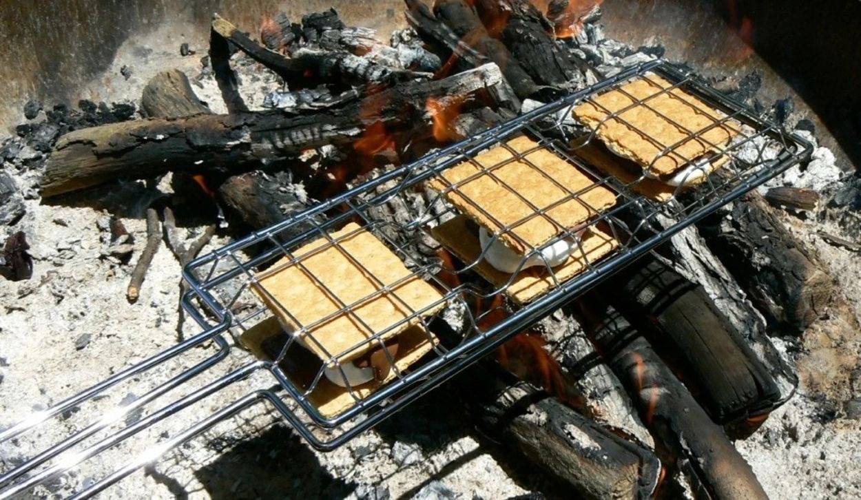 S'mores maker with 3 s'mores toasting over outdoor fire